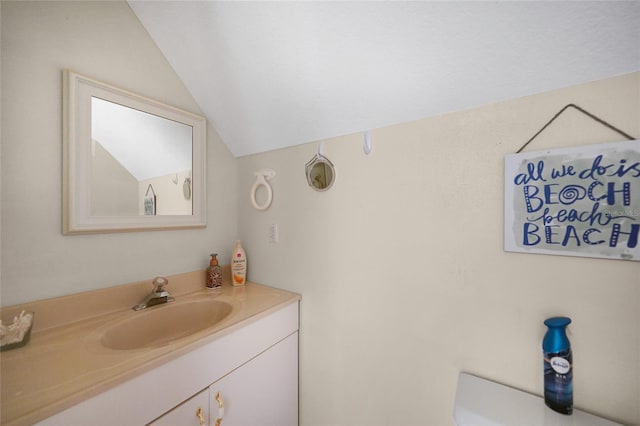 bathroom with vanity, toilet, and vaulted ceiling