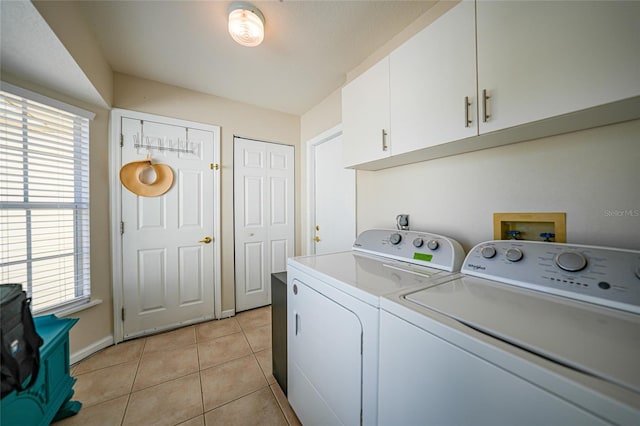 clothes washing area featuring washer and clothes dryer, cabinets, and light tile patterned flooring