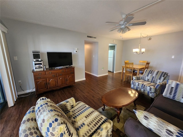 living room featuring dark wood-type flooring, ceiling fan with notable chandelier, and a textured ceiling