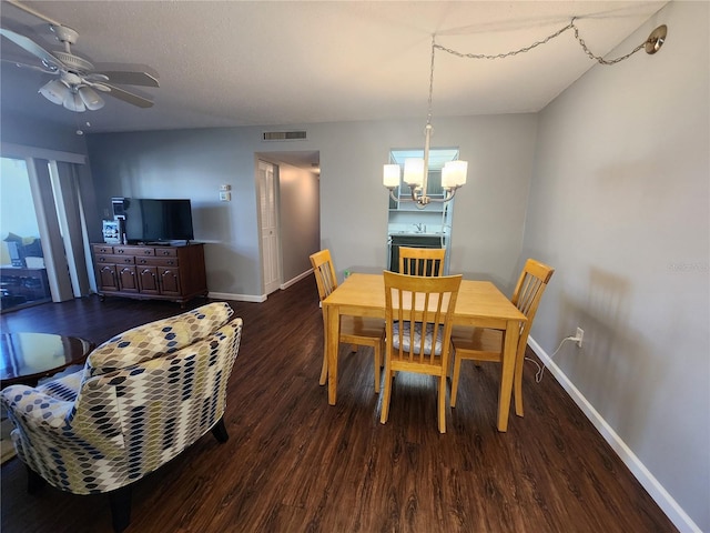 dining room with ceiling fan with notable chandelier and dark wood-type flooring