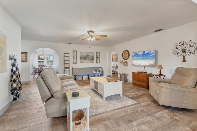 living room with ceiling fan with notable chandelier and light wood-type flooring