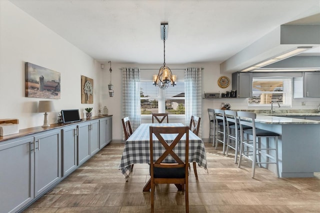 dining room with sink, a chandelier, light hardwood / wood-style floors, and a wealth of natural light