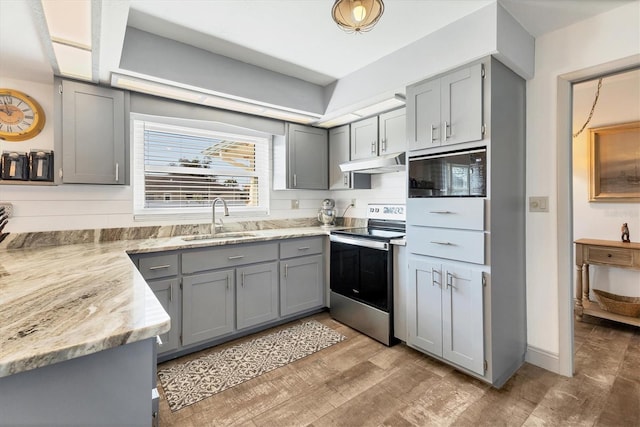 kitchen featuring electric stove, sink, gray cabinets, black microwave, and light wood-type flooring