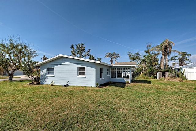 rear view of property with a lawn and a sunroom