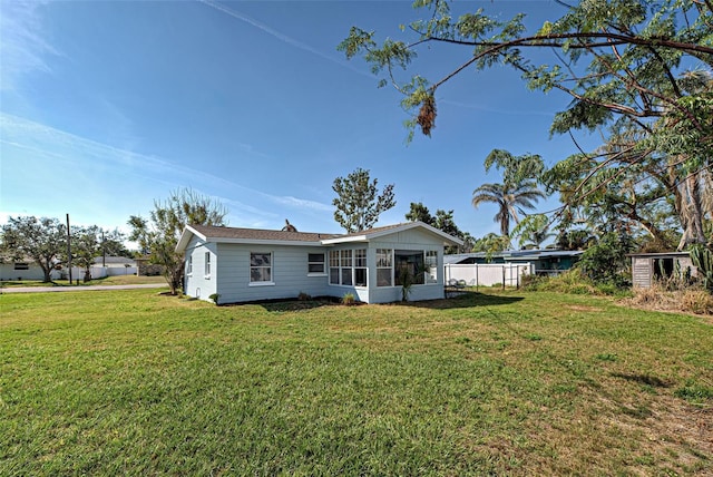 rear view of house with a sunroom and a lawn