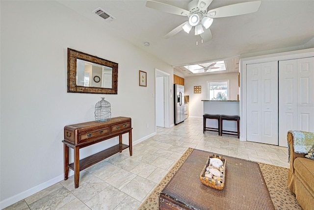 living room with ceiling fan and a skylight