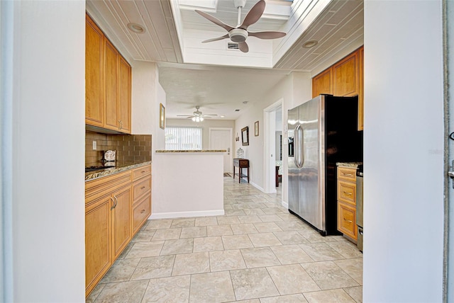 kitchen featuring tasteful backsplash, a tray ceiling, ceiling fan, and stainless steel refrigerator with ice dispenser