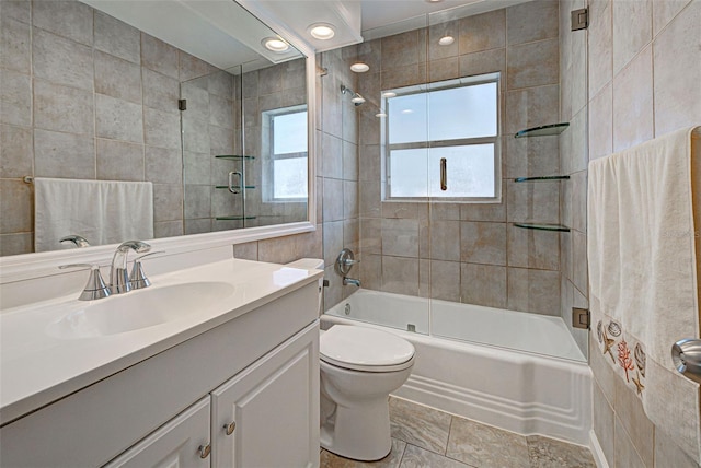 full bathroom featuring vanity, toilet, combined bath / shower with glass door, and tile walls