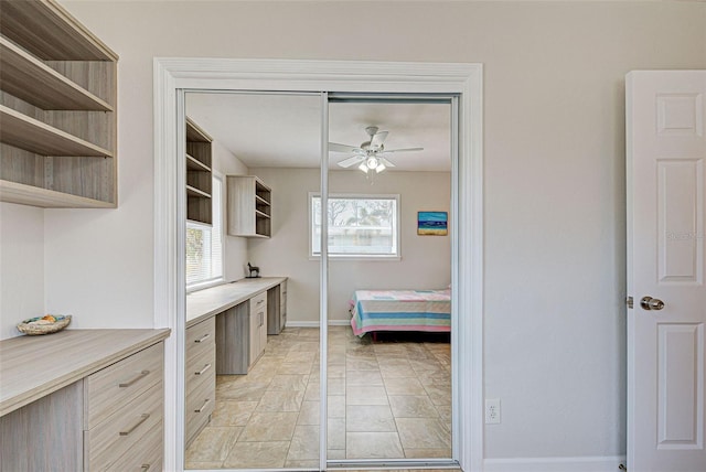 interior space featuring built in desk, ceiling fan, and light tile patterned flooring