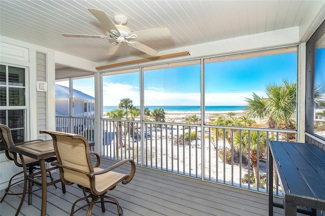 sunroom / solarium with a view of the beach, wood ceiling, ceiling fan, and a water view