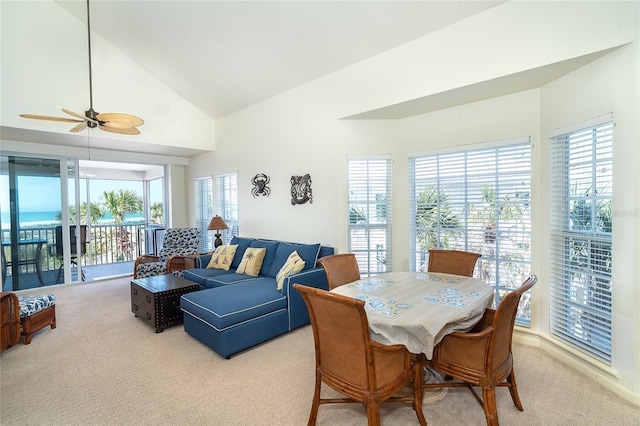 carpeted dining area featuring ceiling fan, high vaulted ceiling, and a healthy amount of sunlight