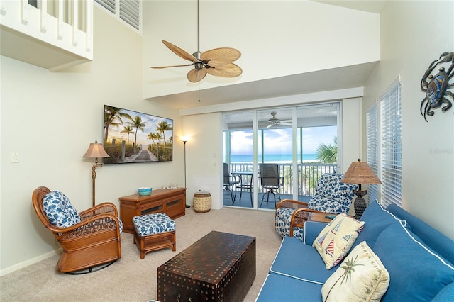 carpeted living room with ceiling fan and a high ceiling