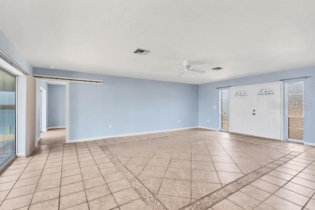 unfurnished room with light tile patterned flooring, ceiling fan, and a barn door