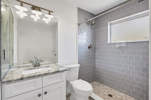 bathroom featuring vanity, tiled shower, and toilet