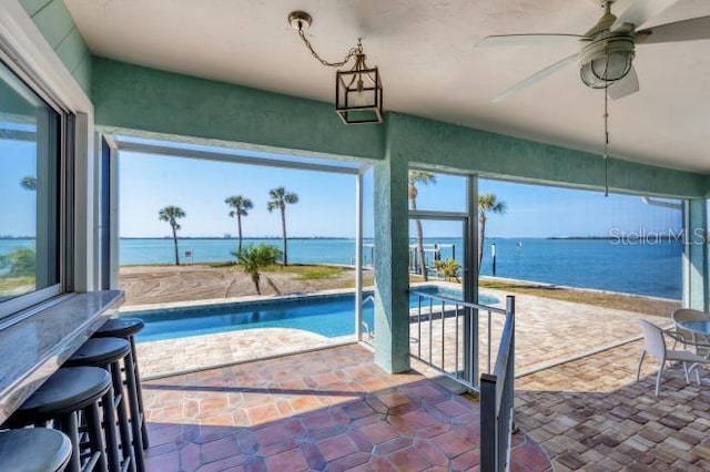 view of pool with a water view, ceiling fan, and a patio area