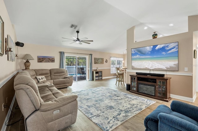 living room with ceiling fan, vaulted ceiling, and light hardwood / wood-style flooring