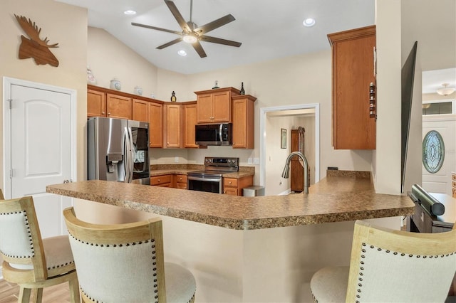 kitchen with sink, appliances with stainless steel finishes, a kitchen breakfast bar, kitchen peninsula, and ceiling fan