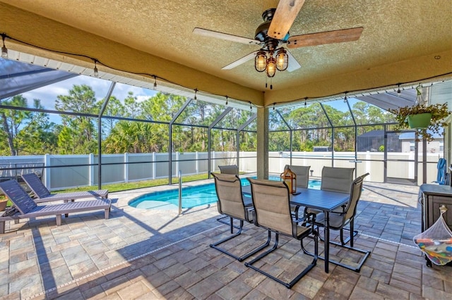 exterior space featuring a fenced in pool, ceiling fan, and glass enclosure