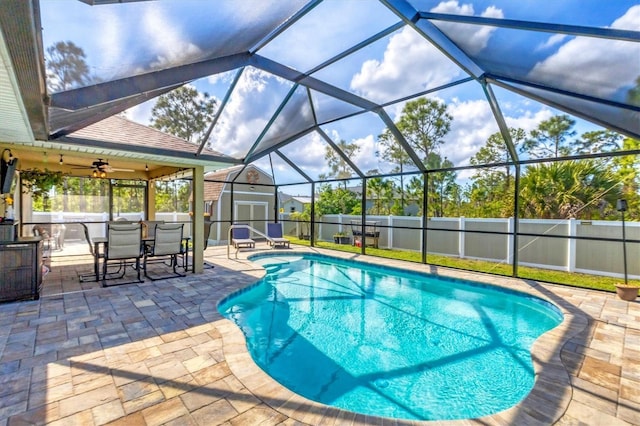 view of pool with a shed, a patio, ceiling fan, and glass enclosure