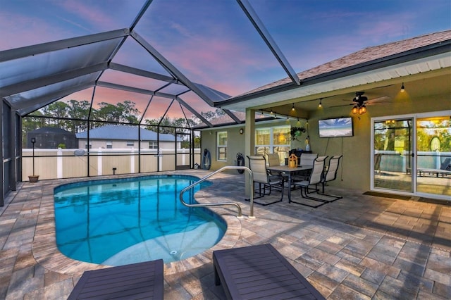 view of swimming pool with ceiling fan, a lanai, and a patio