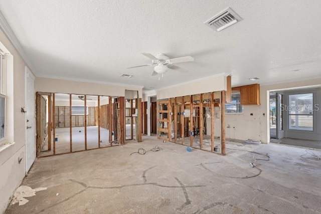 unfurnished living room featuring ornamental molding and a textured ceiling