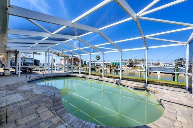 view of pool featuring a water view, a patio area, and glass enclosure