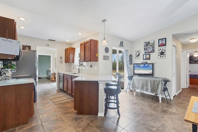 kitchen featuring a kitchen bar, sink, vaulted ceiling, hanging light fixtures, and dishwasher