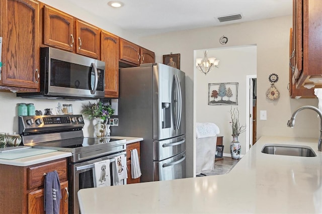 kitchen with an inviting chandelier, sink, hanging light fixtures, and appliances with stainless steel finishes