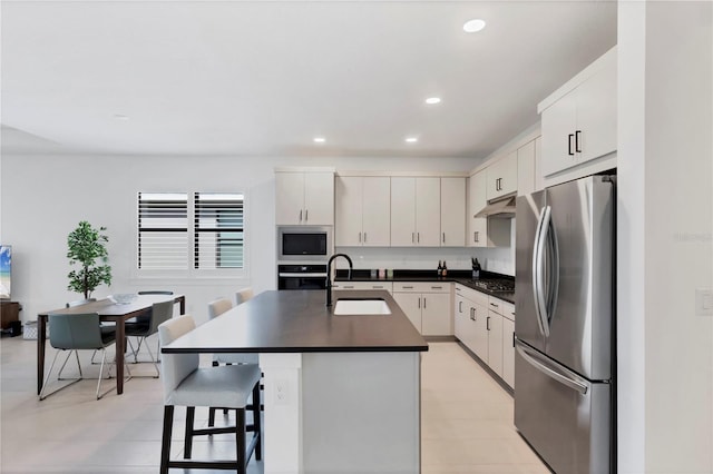 kitchen with a breakfast bar, sink, appliances with stainless steel finishes, an island with sink, and white cabinets