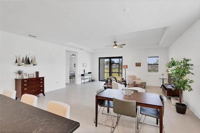 dining space featuring a raised ceiling and ceiling fan