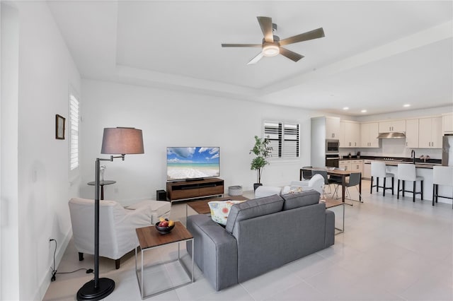 living room with ceiling fan, a healthy amount of sunlight, and a tray ceiling