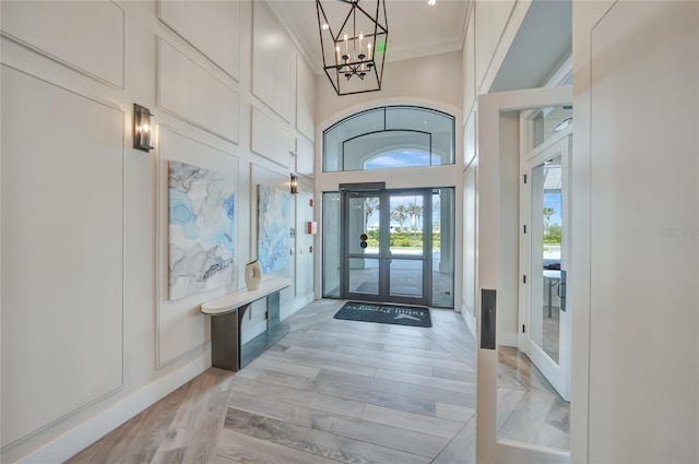 6237 Fish Eagle Ct, Nokomis, FL 34275 - foyer with ornamental molding, a chandelier, light wood-style floors, french doors, and a towering ceiling