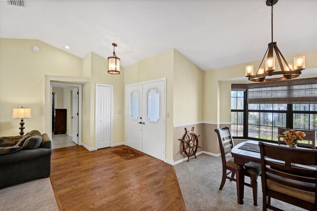 foyer featuring lofted ceiling, wood finished floors, baseboards, carpet floors, and a notable chandelier
