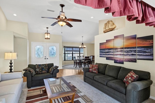 living room with lofted ceiling, visible vents, and ceiling fan with notable chandelier