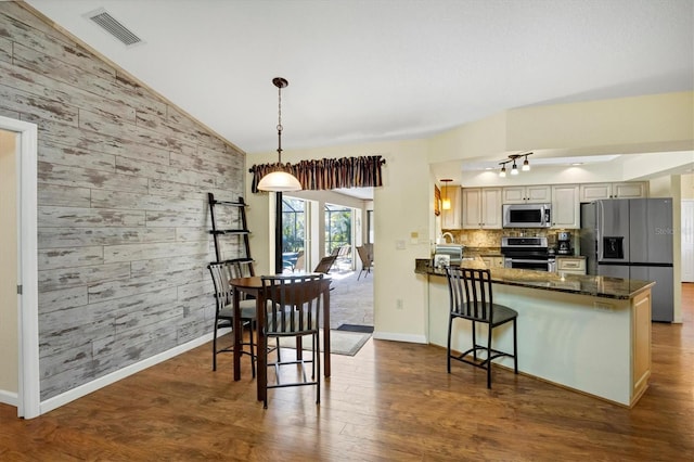 dining space featuring lofted ceiling, visible vents, dark wood-style flooring, wooden walls, and baseboards