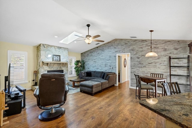 living room featuring ceiling fan, lofted ceiling with skylight, a healthy amount of sunlight, and wood finished floors