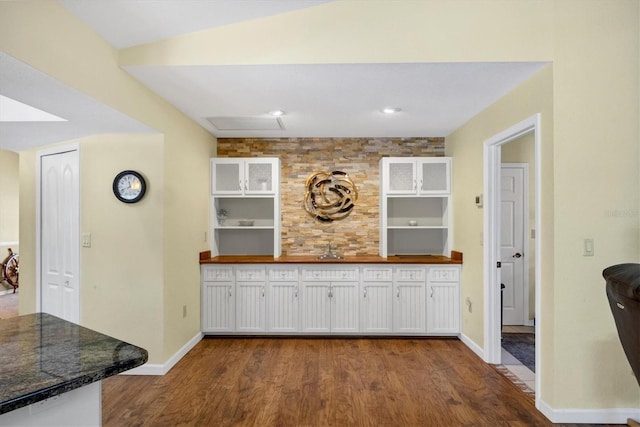 bar with decorative backsplash, dark wood-style flooring, baseboards, and a sink