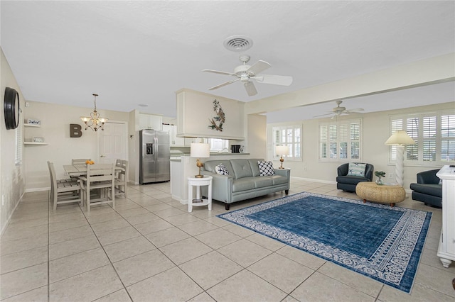 tiled living room with ceiling fan with notable chandelier