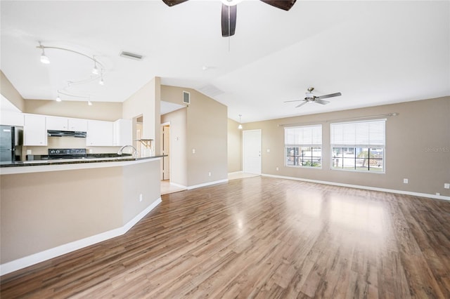 unfurnished living room featuring ceiling fan, sink, vaulted ceiling, and light hardwood / wood-style flooring