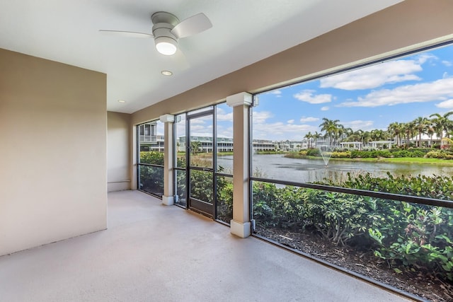 unfurnished sunroom with a water view and ceiling fan