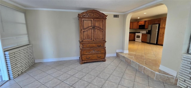 kitchen with crown molding, light tile patterned flooring, stainless steel refrigerator, and white range with electric cooktop