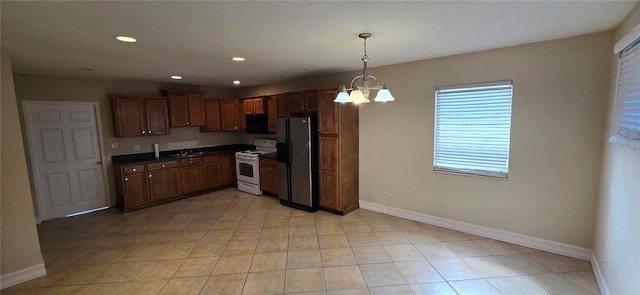 kitchen with electric stove, sink, stainless steel refrigerator, an inviting chandelier, and hanging light fixtures