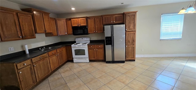 kitchen with sink, electric range, light tile patterned flooring, and stainless steel refrigerator with ice dispenser