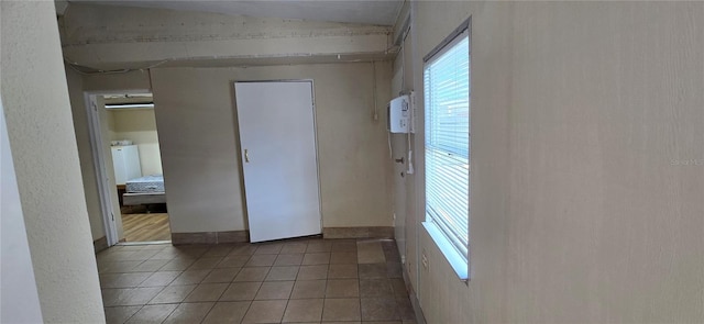 tiled empty room with lofted ceiling and washer / dryer