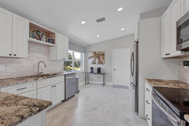 kitchen featuring light stone counters, stainless steel appliances, a sink, visible vents, and white cabinets