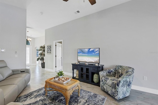 living room with ceiling fan with notable chandelier, visible vents, and baseboards