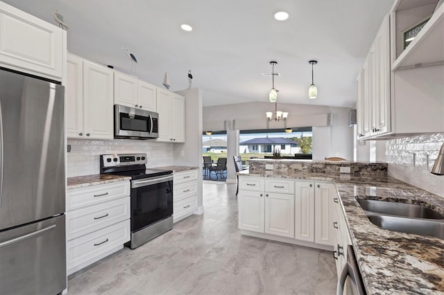 kitchen with a notable chandelier, vaulted ceiling, stainless steel appliances, white cabinetry, and a sink