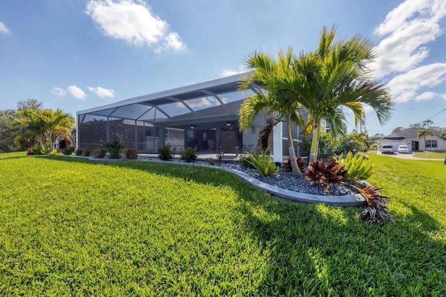 rear view of property with a lawn and a lanai