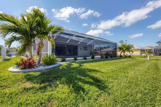 rear view of house with a lanai and a yard