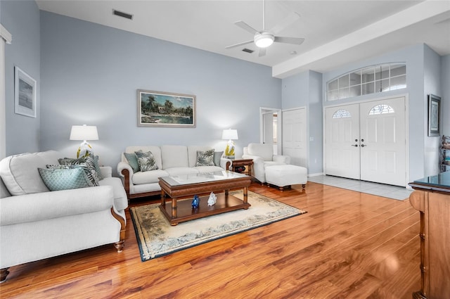 living room featuring hardwood / wood-style flooring, a towering ceiling, and ceiling fan